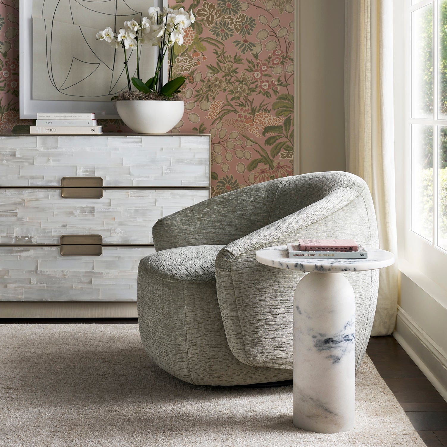 Modern living room with a gray armchair, CANYON marble side table, and decorative elements.