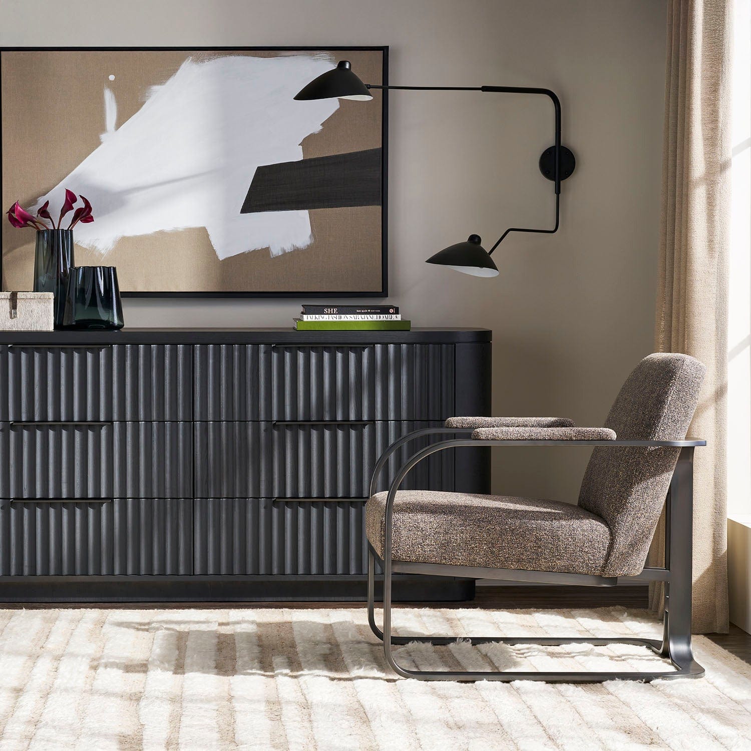 Modern living room with a black dresser, gray armchair, and abstract art on the wall.