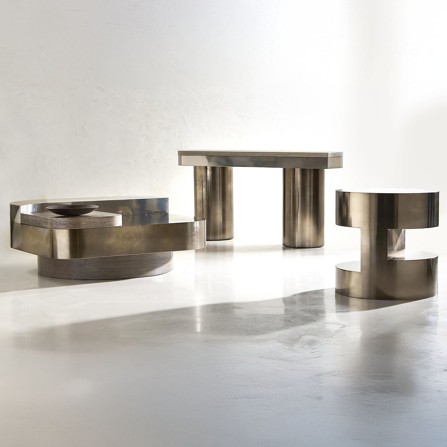 Set of three metallic side tables on a white background