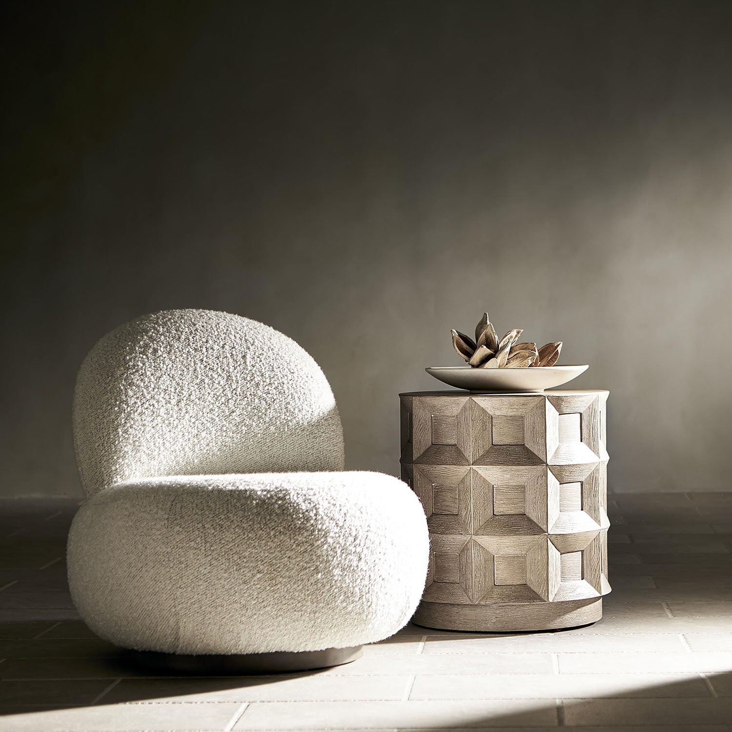 Textured Lulu chair and geometric-patterned side table against a dark wall.
