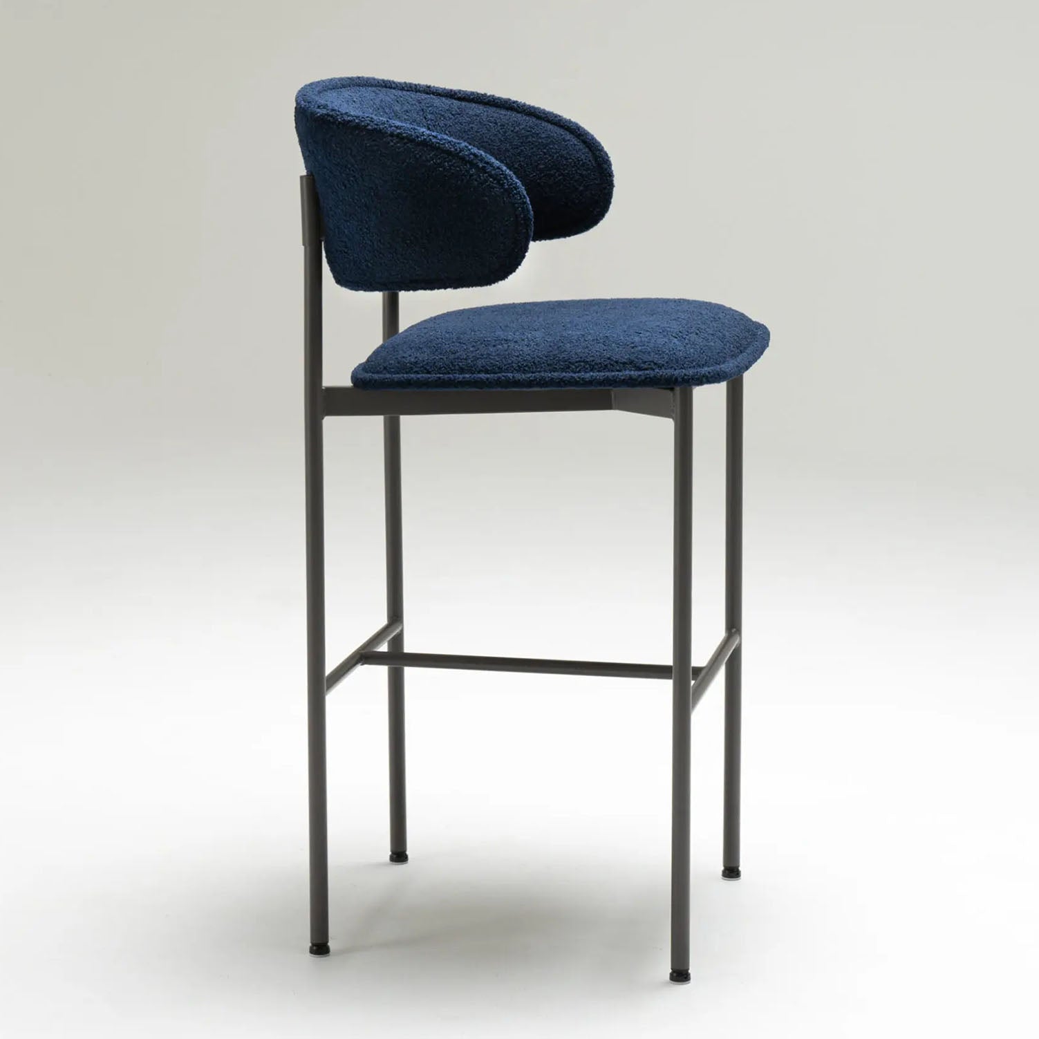 Blue chloe bar stool with black metal frame facing the side on a white background