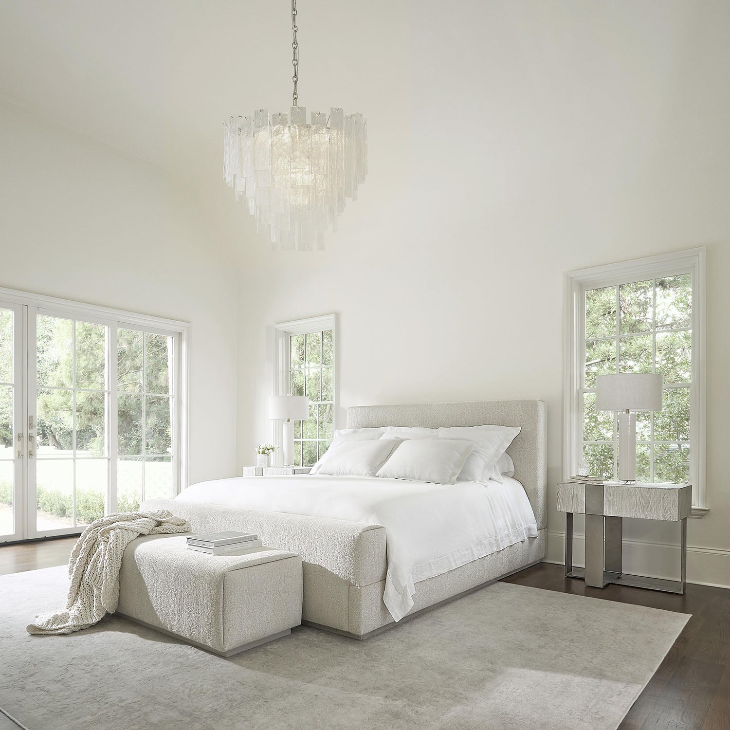 Modern bedroom with a chandelier, bed, and side table and a Tempo bench at the foot of the bed.