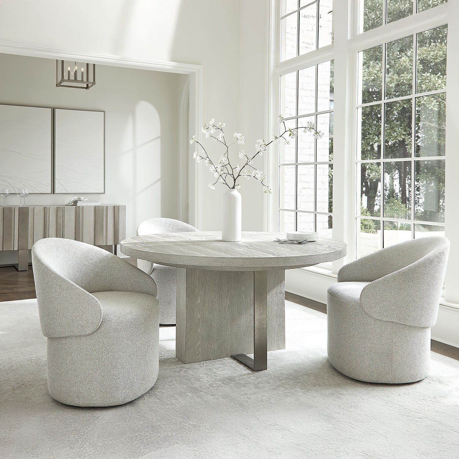 Modern dining room with a round marble table and Tempo chairs in a bright room with large windows.
