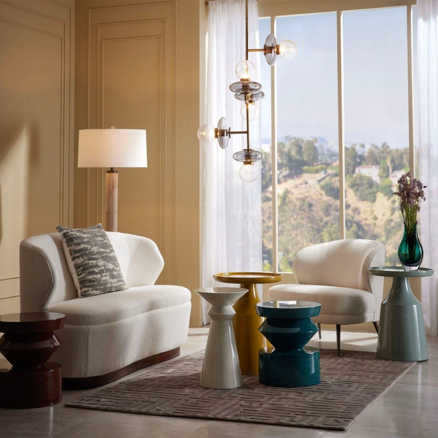 Modern living room with white armchairs, side tables, and a large window.