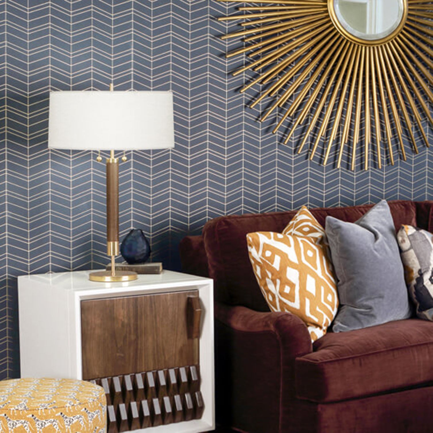 Living room with DEXTER TABLE LAMP, brown sofa, gold mirror, and decorative pillows against a blue geometric wallpaper.